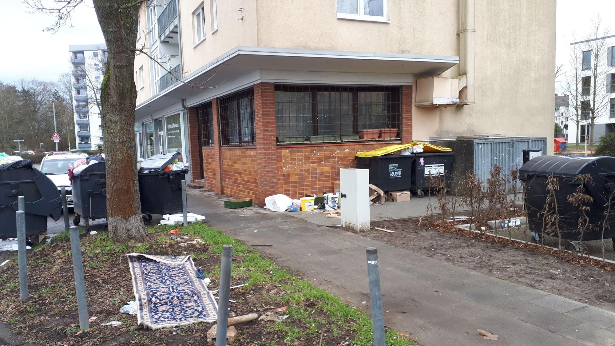 Das Bild zeigt das Haus August-Haas-Straße 1, mit der leerstehenden Gaststätte im Erdgeschoss. In der Umgebung sammelt sich der Müll.