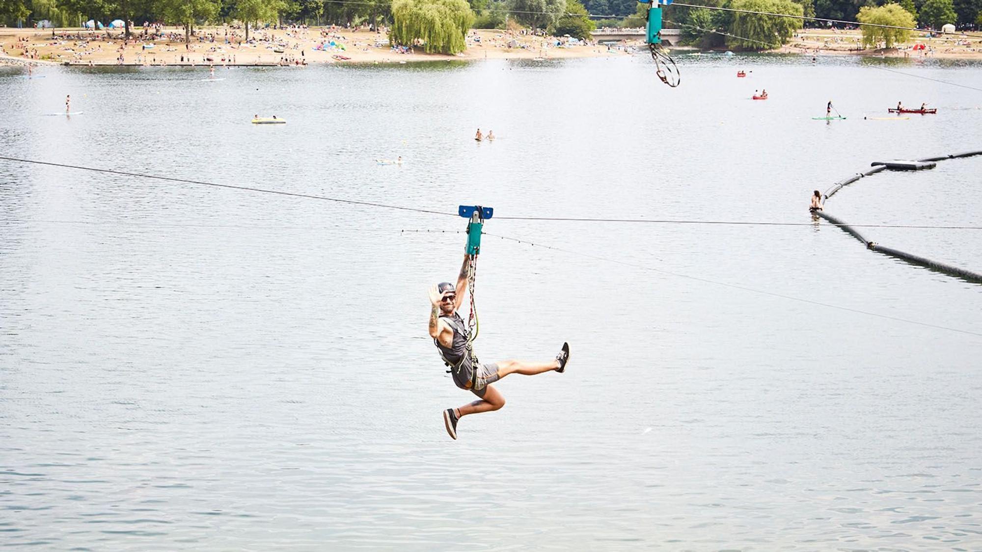 Mann fährt an einer Seilbahn über einen See
