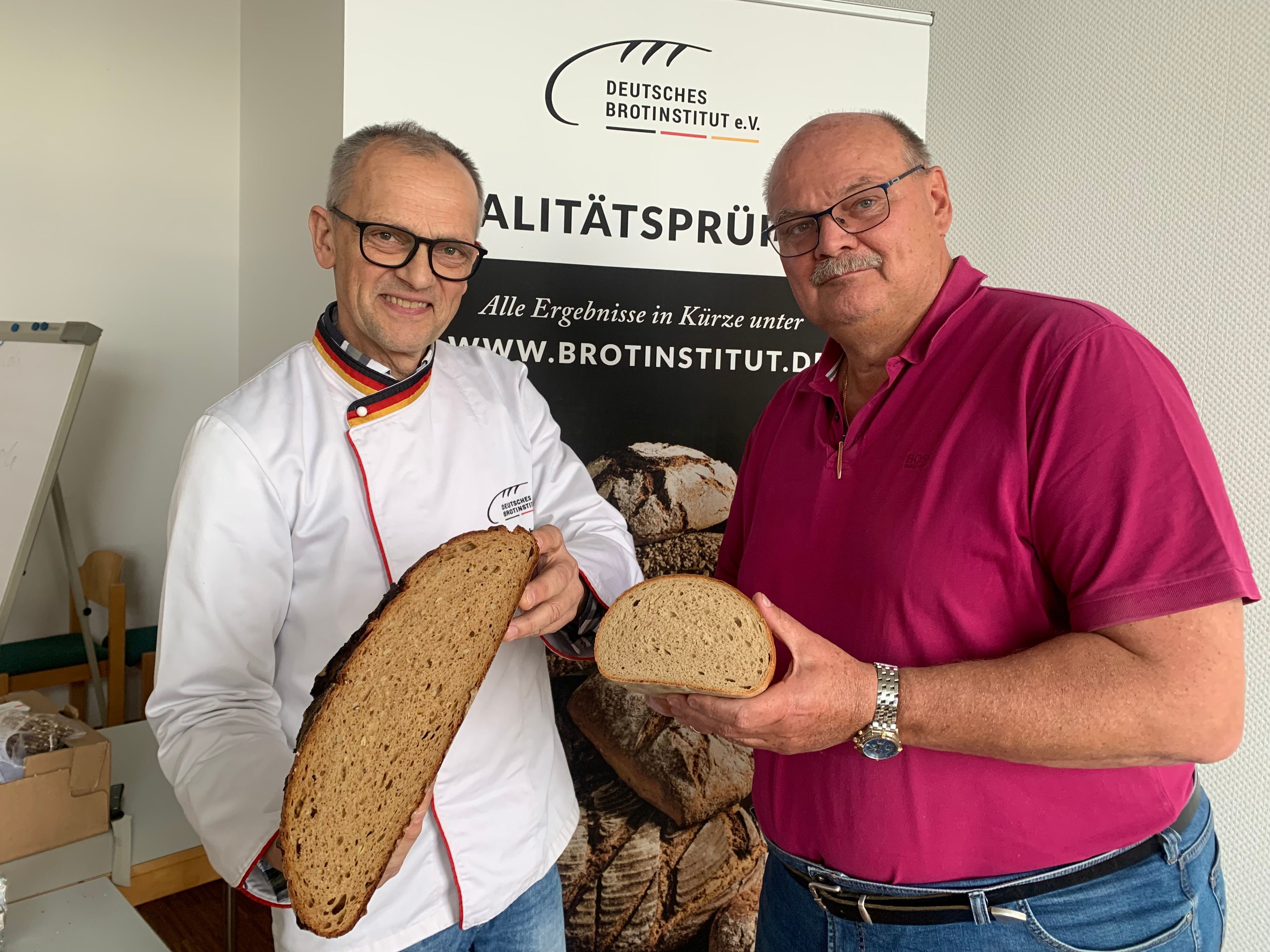 Zwei Männer halten aufgeschnittenes Brot in den Händen.