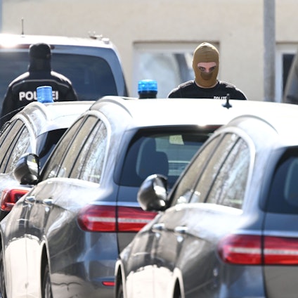 Vermummte Polizisten stehen während der Razzia im „Reichsbürger“-Milieu in Reutlingen an Fahrzeugen.