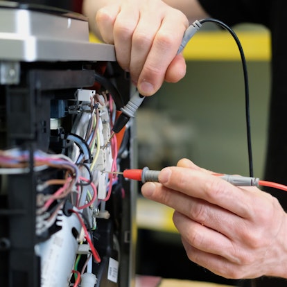 An einem Kaffee-Vollautomaten in einer Reparaturwerkstatt werden elektronische Messgrößen ermittelt.