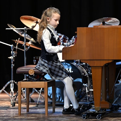 Ein Mädchen sitzt an einem Flügel und spielt.