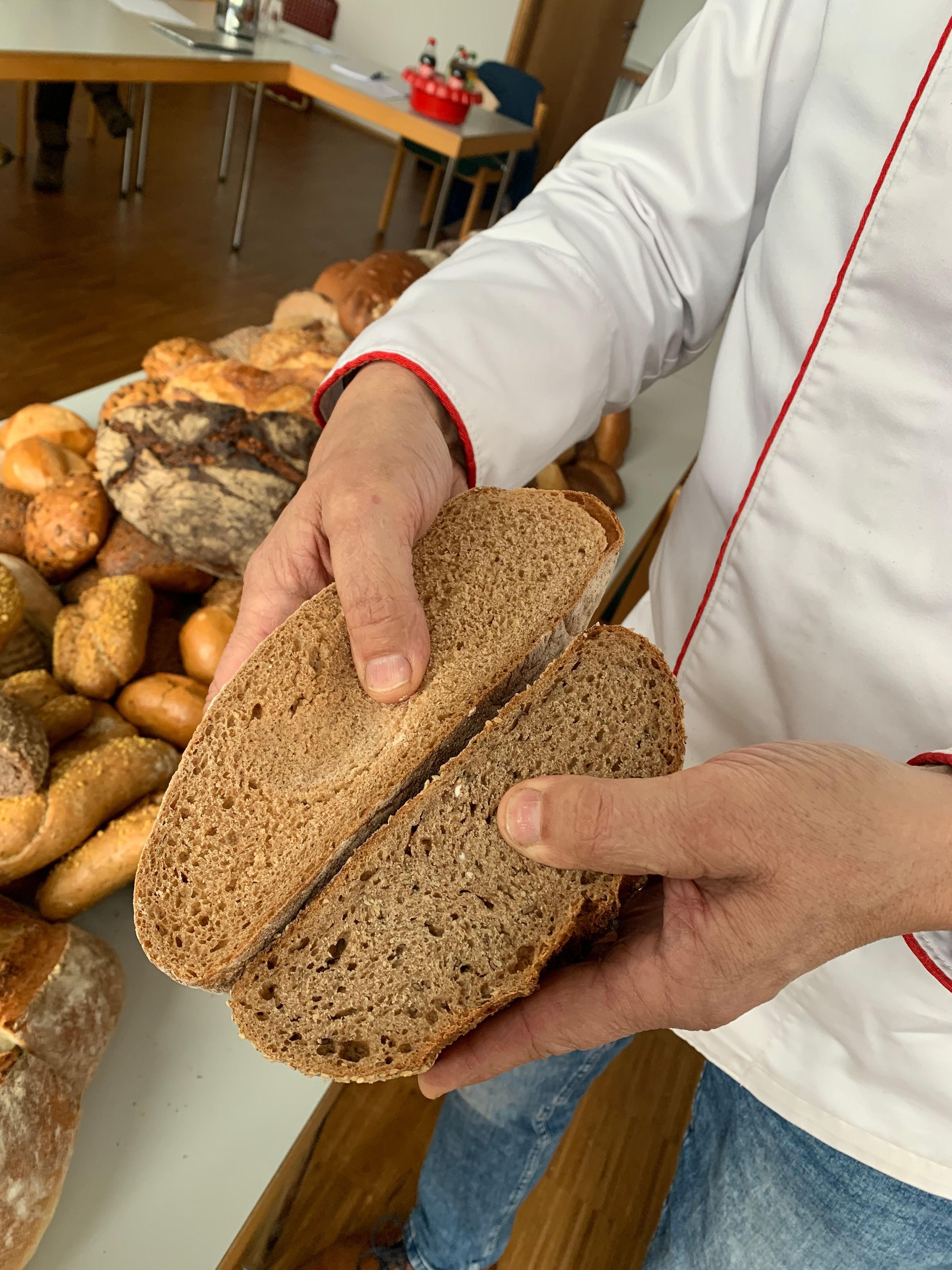 Der Brottester hält zwei Stücke Brot in der Hand und drück mit den Daumen in das Brot hinein.