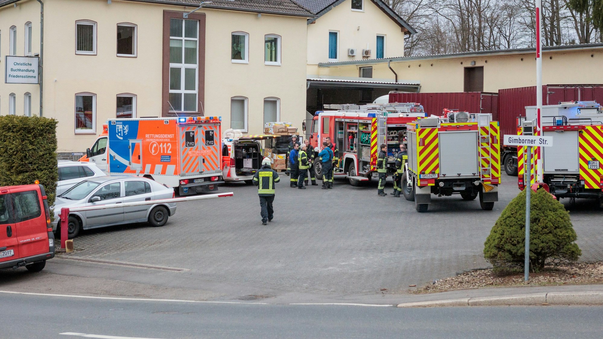 Fahrzeuge der Feuerwehr und des Rettungsdienstes stehen vor einem Gebäude.