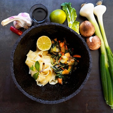 In einer Schüssel liegen die Tagliatelle mit Gemüse. Neben dem Teller liegen die Zutaten als Deko.