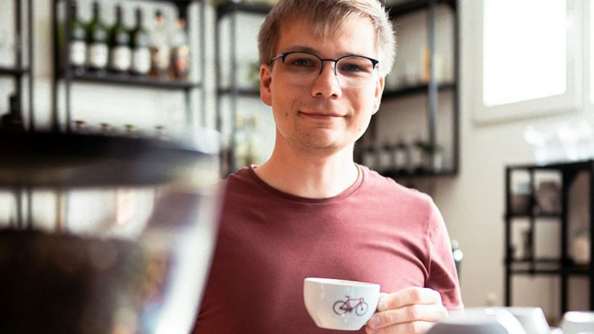 Ein Barista hat eine Kaffeetasse in der Hand.