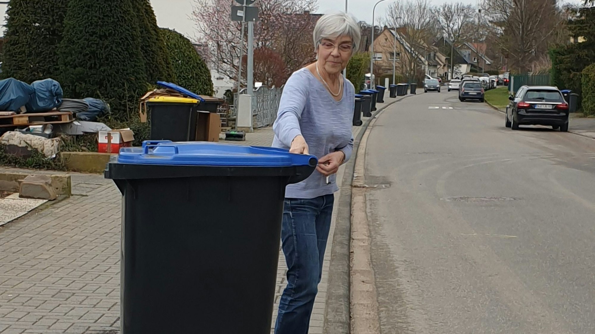 Anwohnerin Ulrike Schwering stellt eine Mülltonne auf den Gehweg.