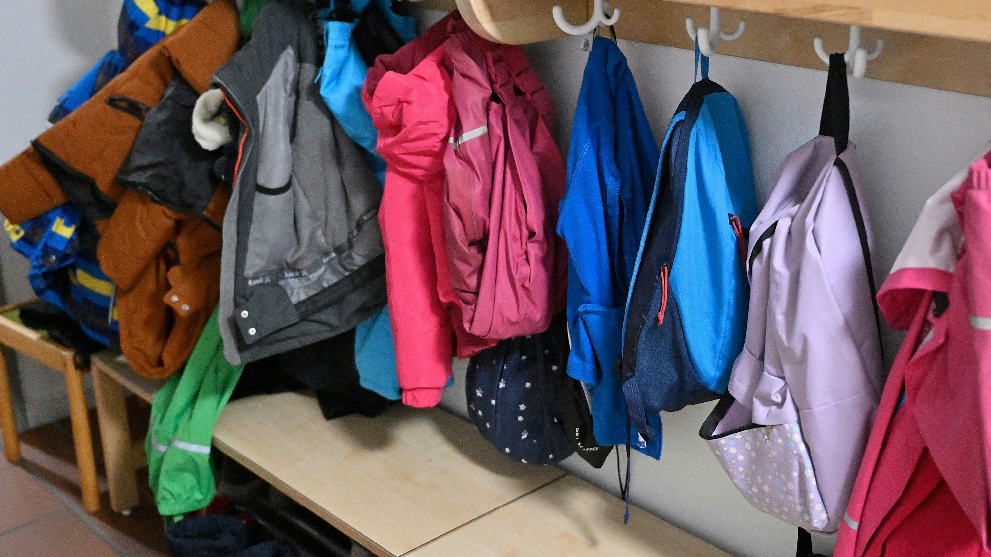 Jacken und Mäntel hängen an einer Garderobe.