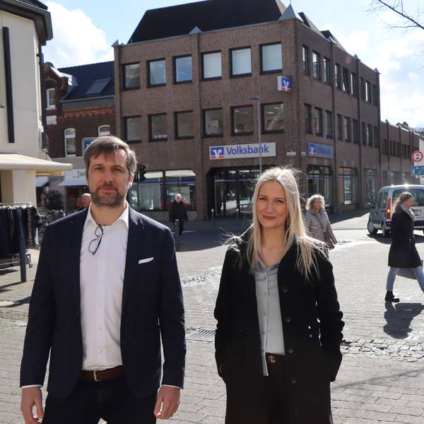 Die Juristen Alina Kriechel und Alrik Haug finden, dass das Linksabbiegeverbot schnell wieder aufgehoben werden soll. Sie stehen in Erftstadt-Lechenich. Im Hintergrund ist zu sehen, dass ein Pkw links abbiegt, obwohl das Verkehrszeichen einen Pfeil nach rechts zeigt.