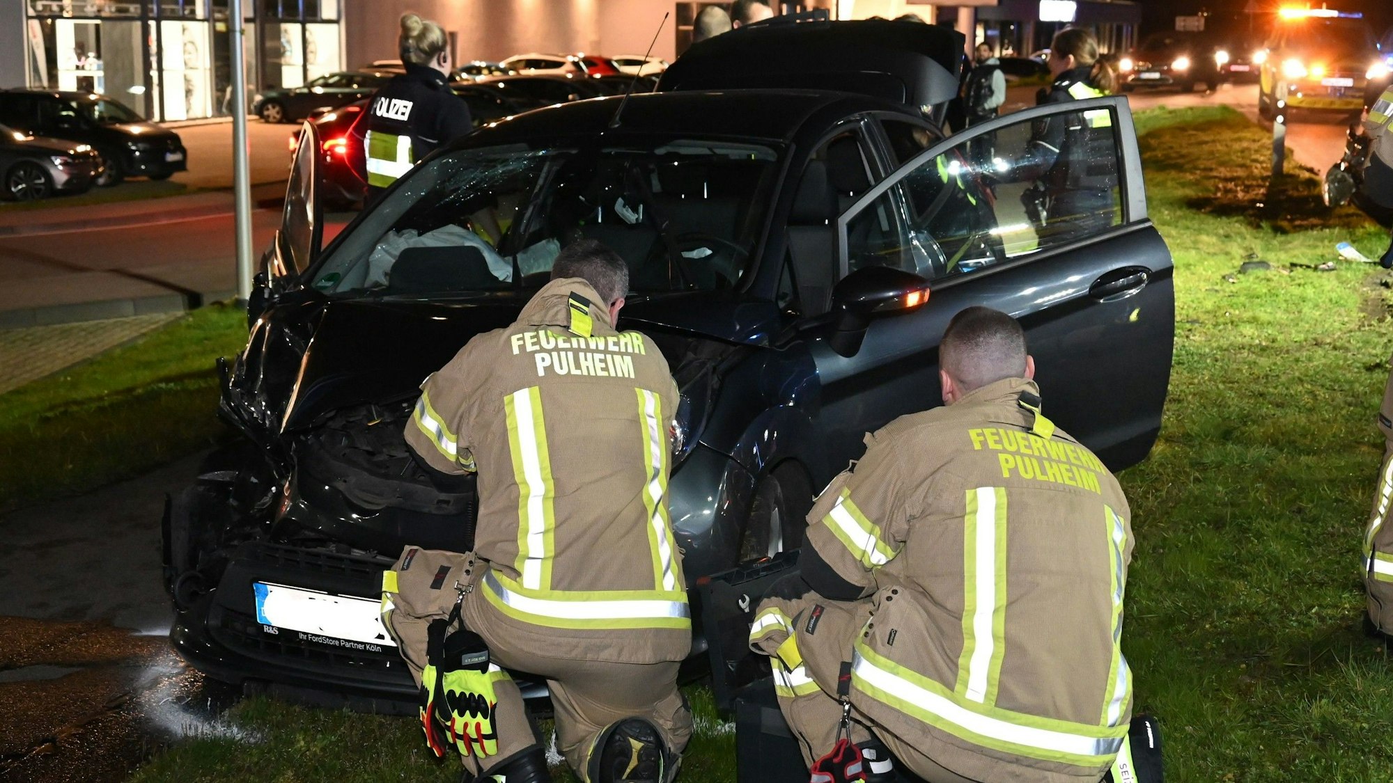 Einsatzkräfte der Feuerwehr Pulheim vor einem verunfallten Pkw.