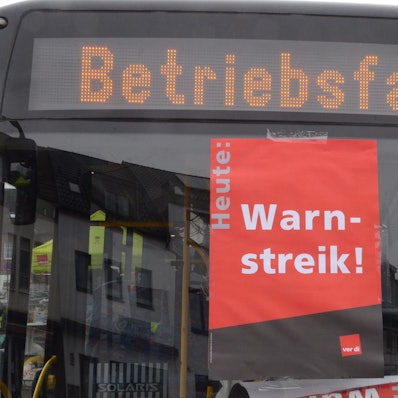 In einer Busscheibe klebt ein Plakat mit „Warnstreik“
