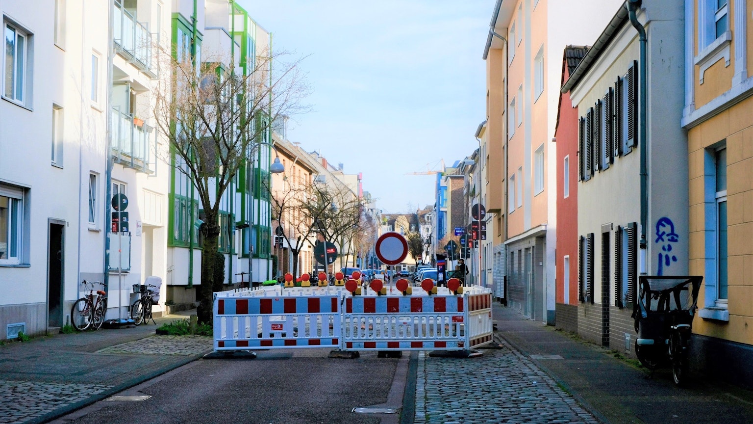 Schilder und Baustellenabsperrungen weisen an der Straße auf eine Sperrung hin.
