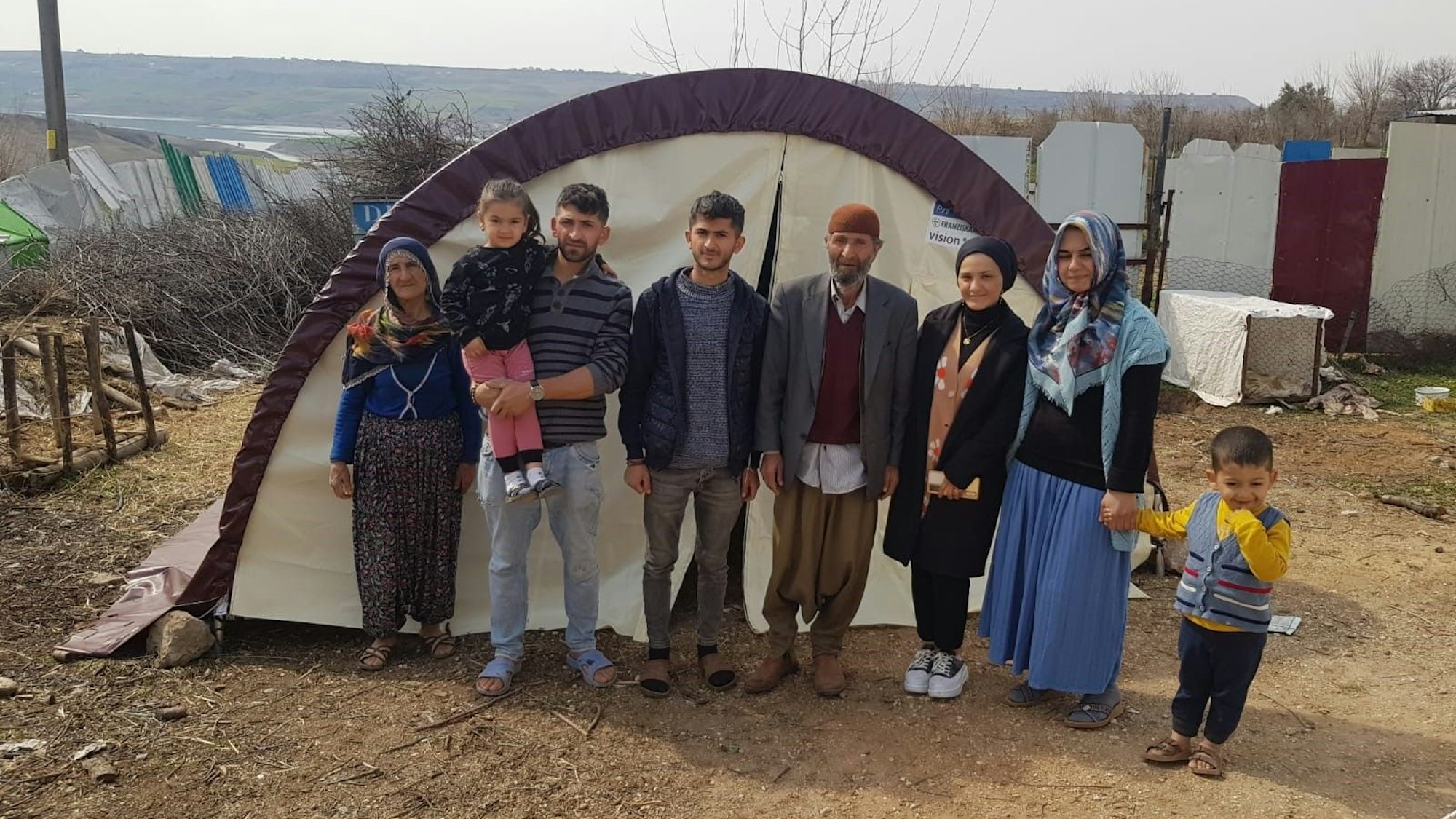 Eine Familie steht vor einem Zelt.