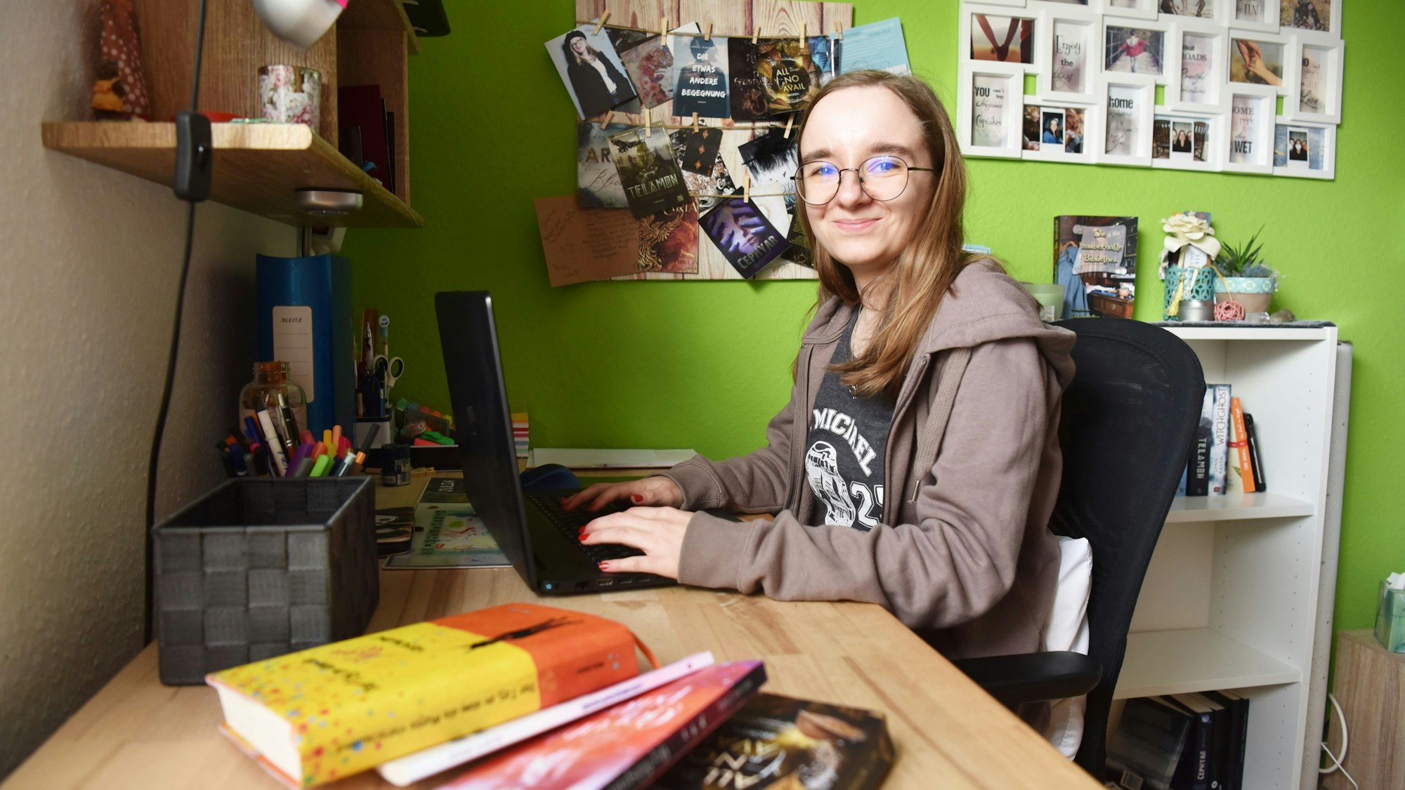 Julia Abel sitzt in ihrem Zimmer am Schreibtisch und tippt auf ihrem Laptop.