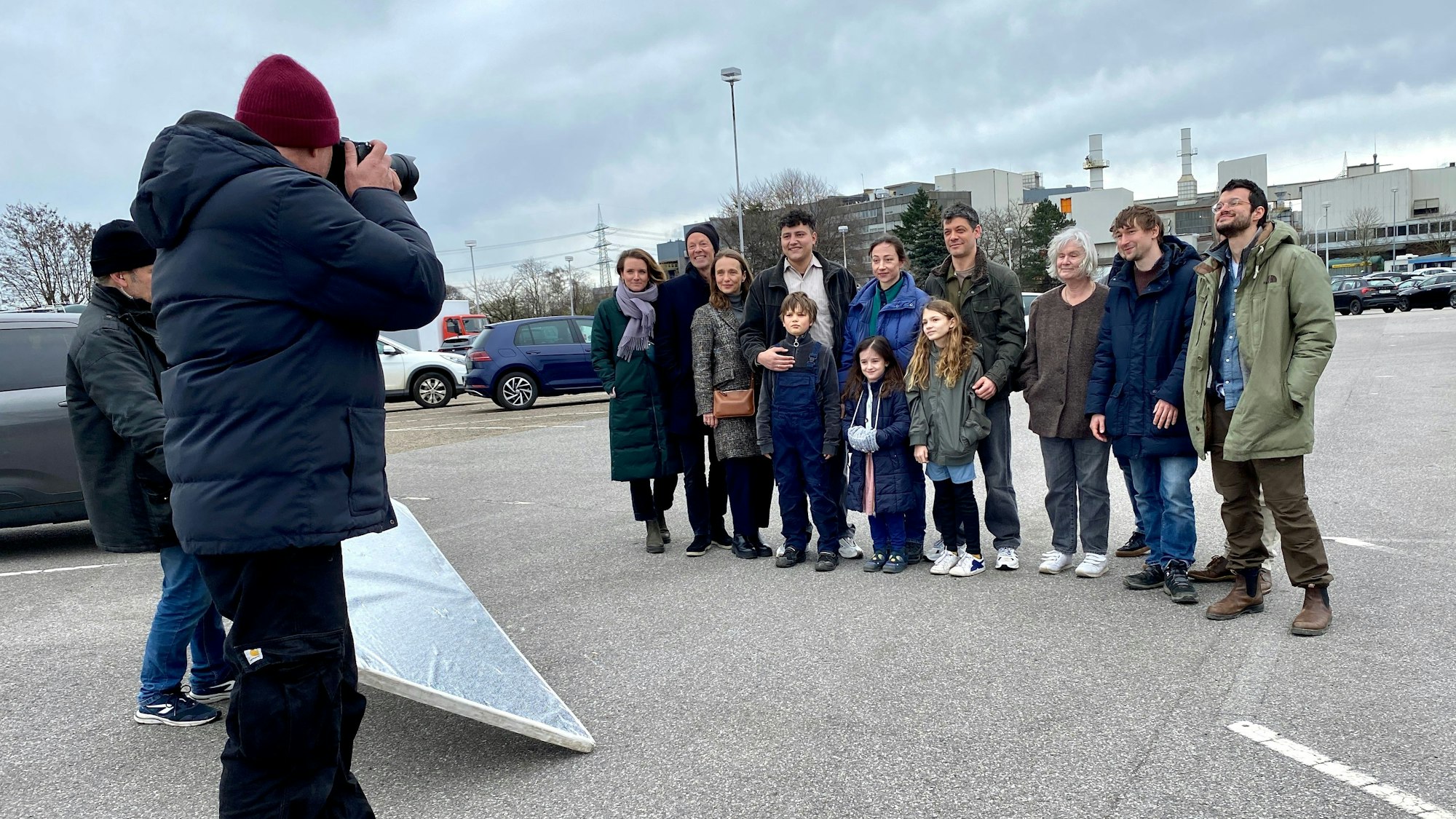 Eine Gruppe Menschen verschiedenen Alters wird von einem Fotografen fotografiert.
