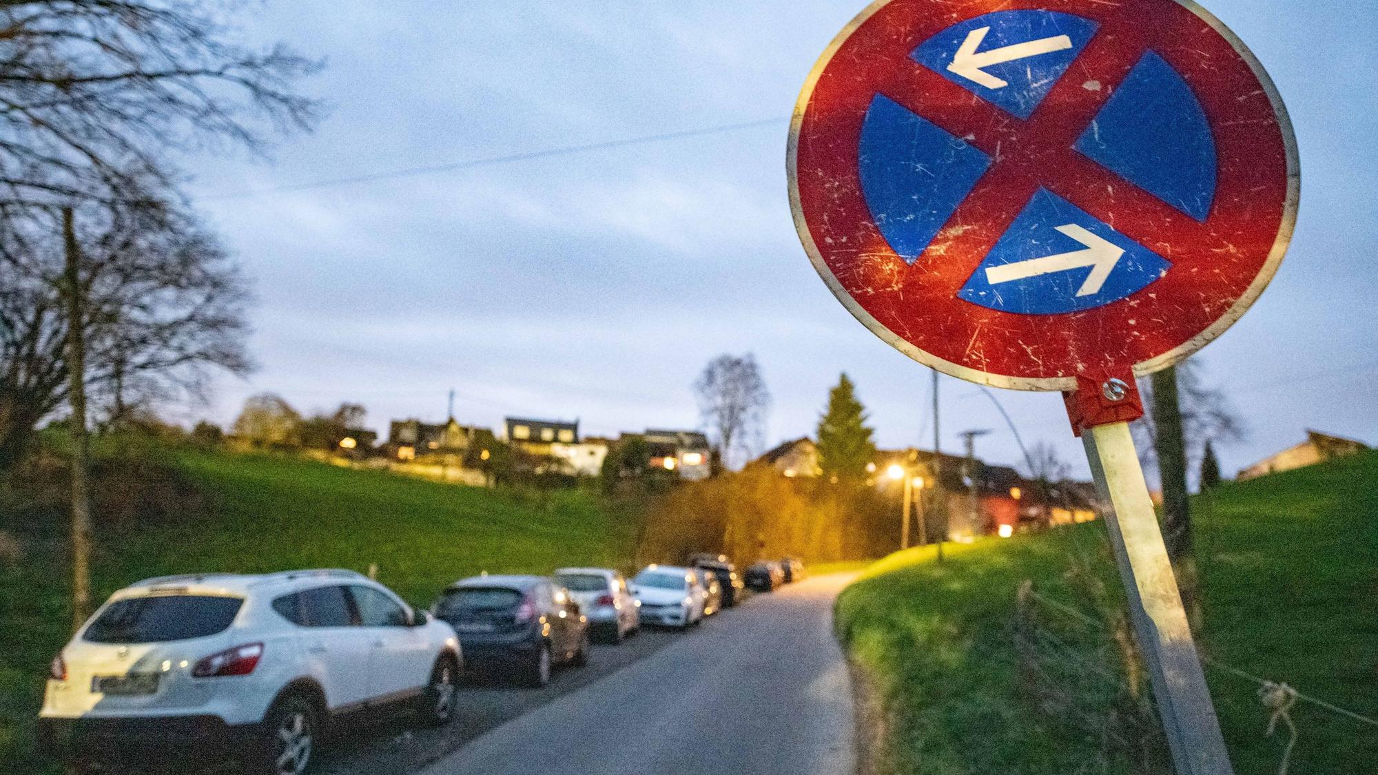 Mehrere Autos parken hintereinander in einer ländlichen Gegend.