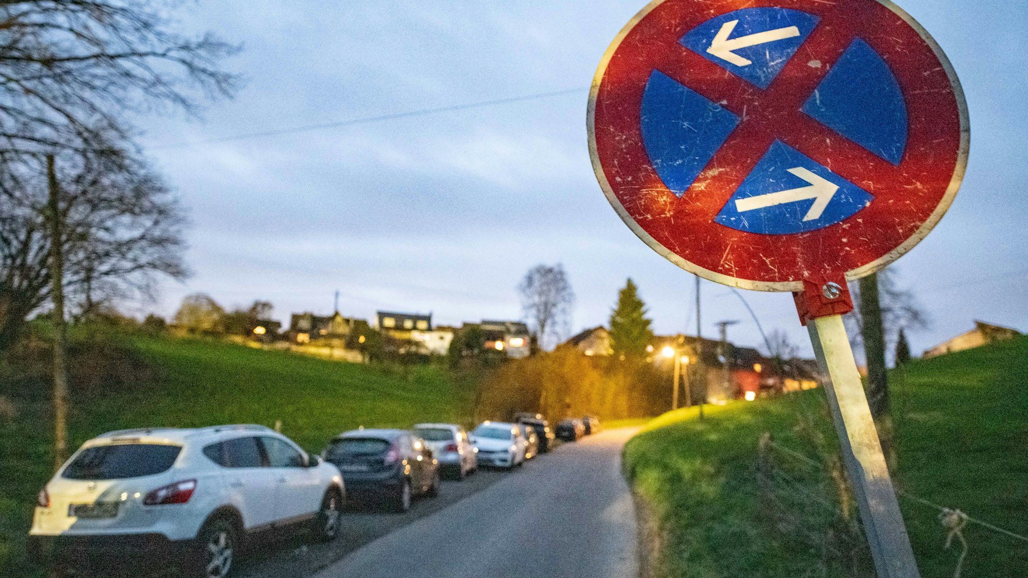 Mehrere Autos parken hintereinander in einer ländlichen Gegend.