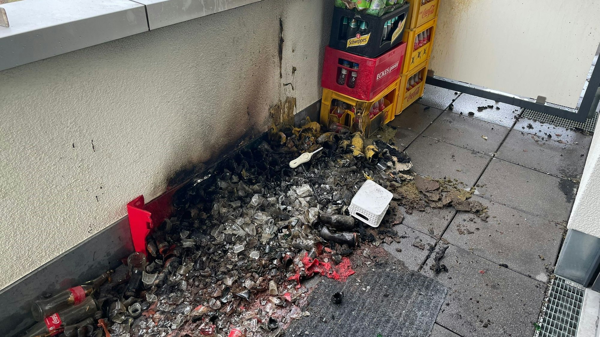 Verbrannte Dosen und Plastikflaschen auf einem Balkon.