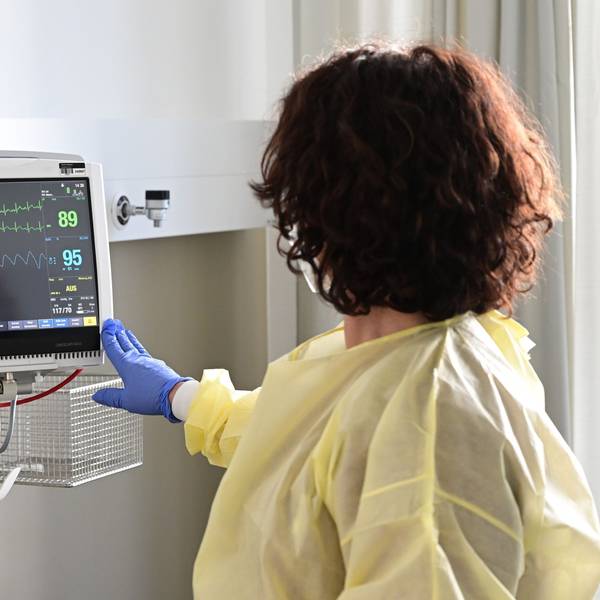 Eine Pflegerin schaut in einem Krankenzimmer im Klinikum Stuttgart auf einen Monitor einer Patientin.