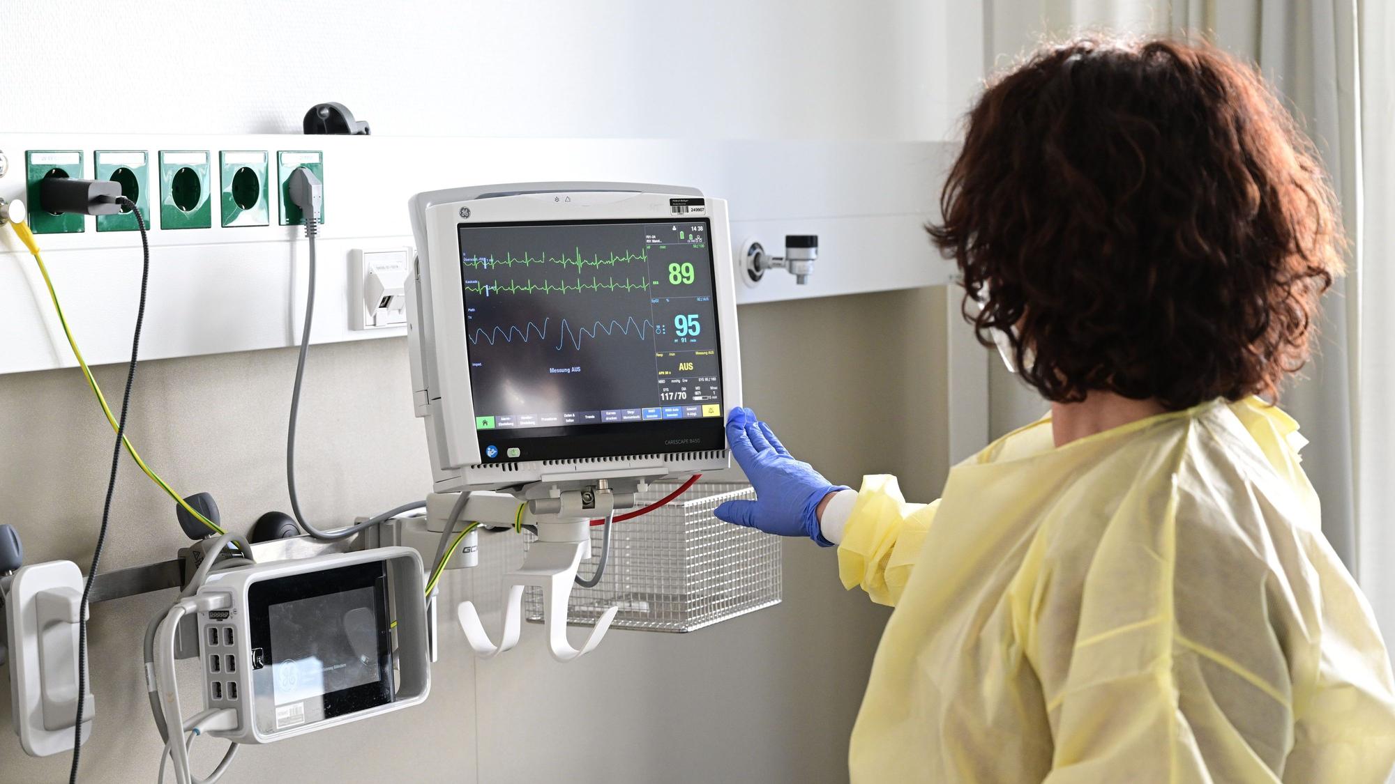 Eine Pflegerin schaut in einem Krankenzimmer im Klinikum Stuttgart auf einen Monitor einer Patientin.