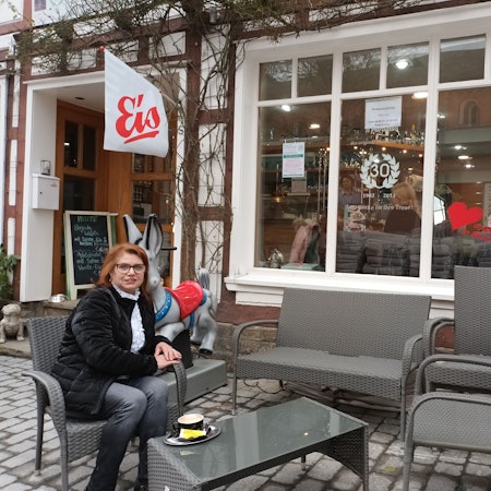 EIne rothaarige Frau mit Brille, Giuseppa Collina, sitzt vor der Eisdiele „Il Paradiso“