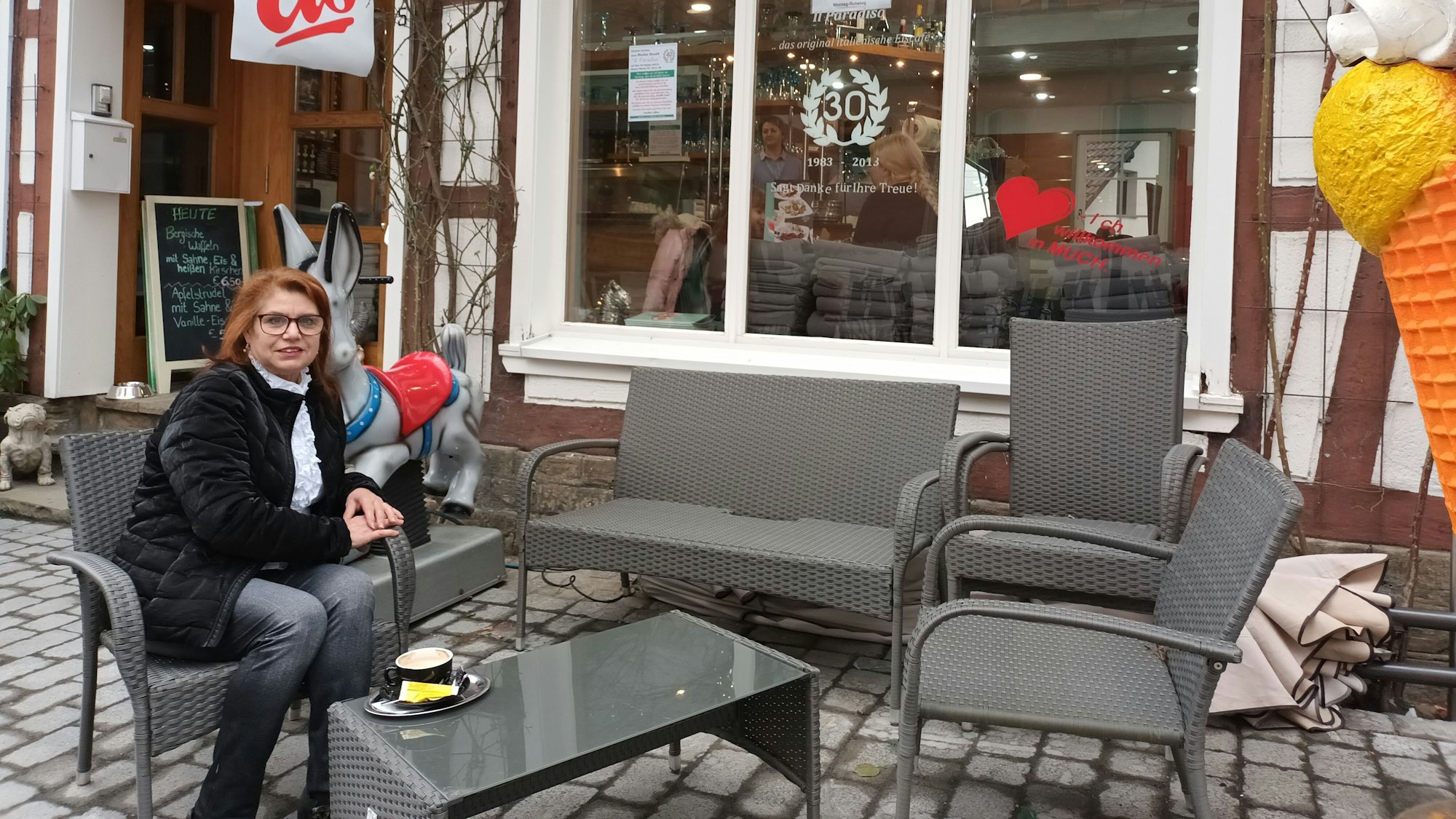 EIne rothaarige Frau mit Brille, Giuseppa Collina, sitzt vor der Eisdiele „Il Paradiso“
