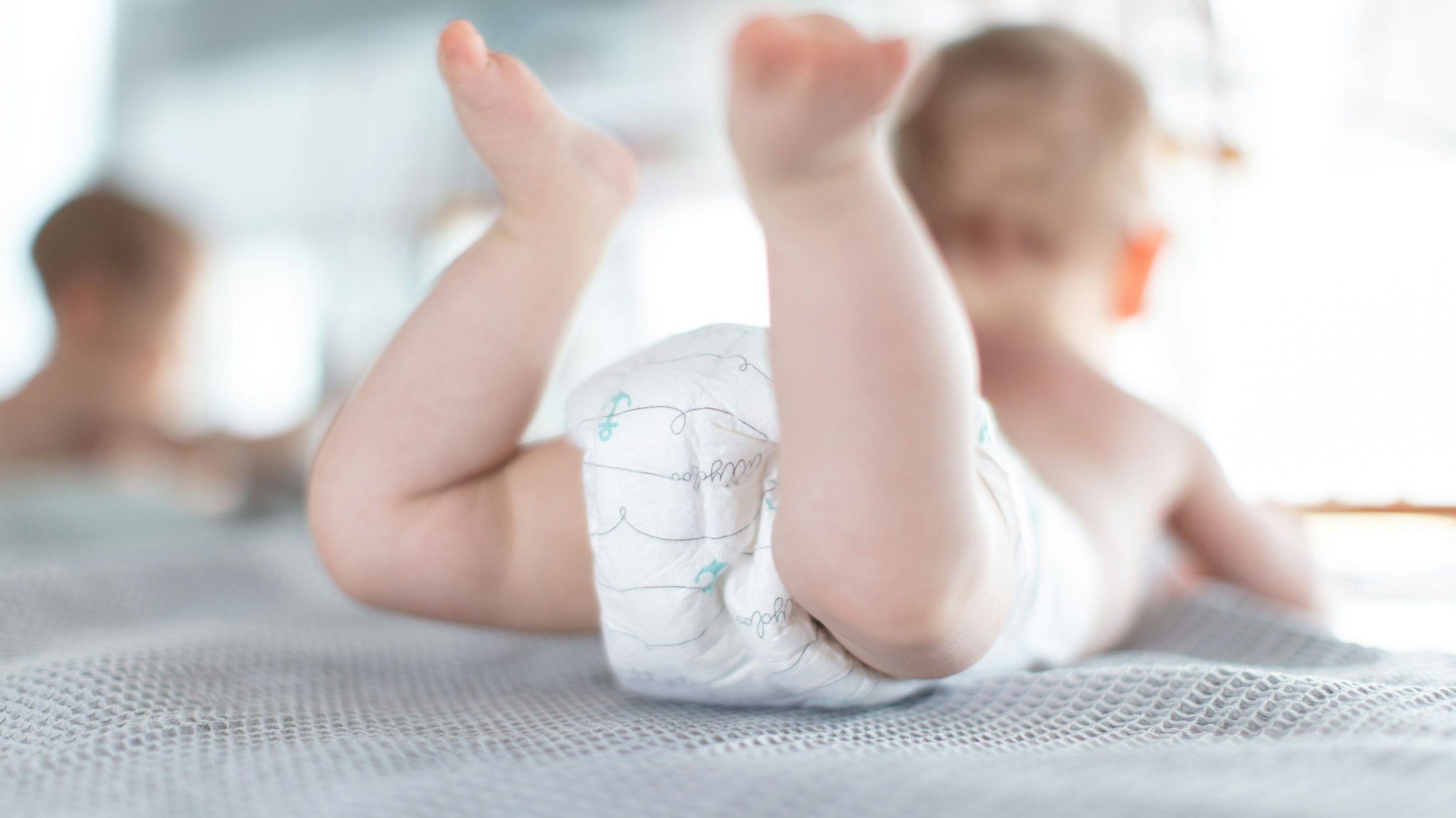 Ein Baby in Windeln liegt auf dem Bauch.