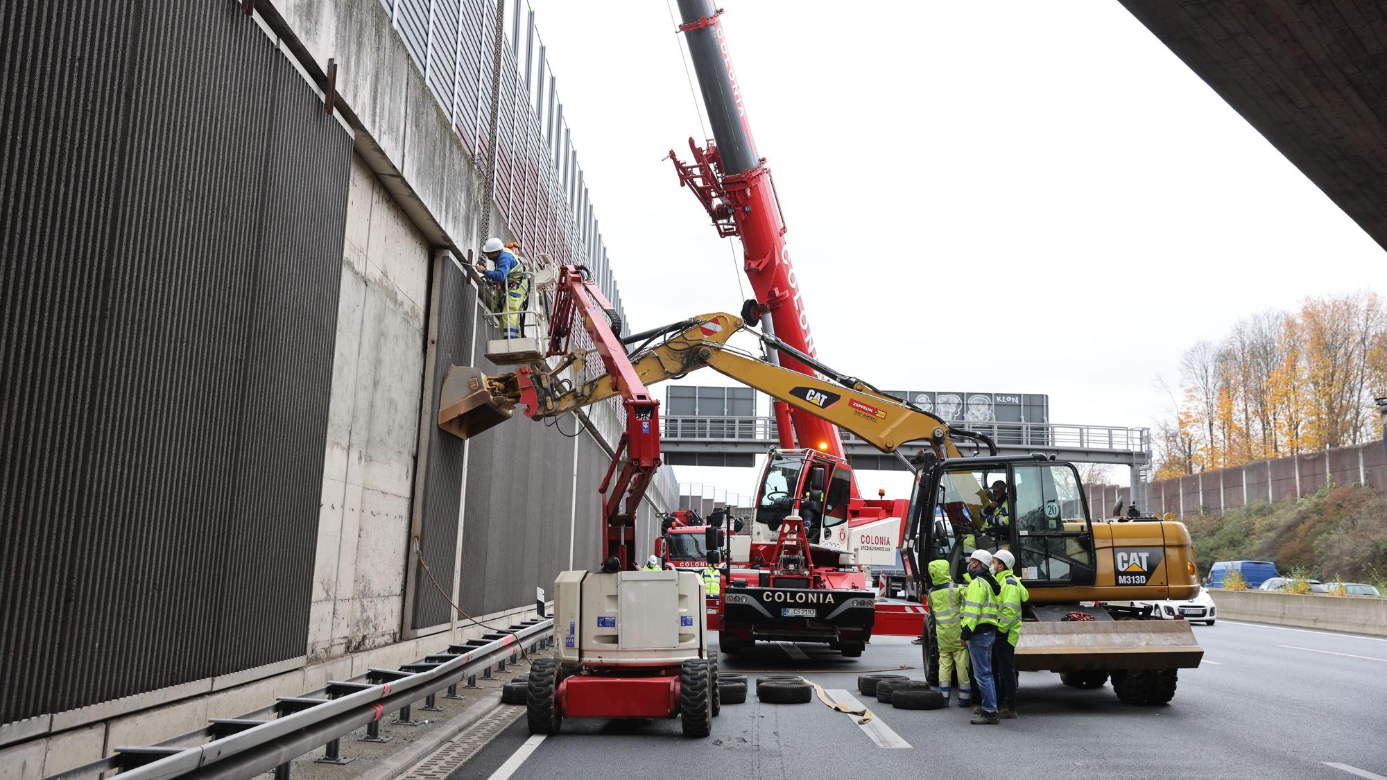 Kriminalbeamte und Mitarbeiter von Straßen NRW untersuchen die Betonplatten an der Lärmschutzwand der A3.