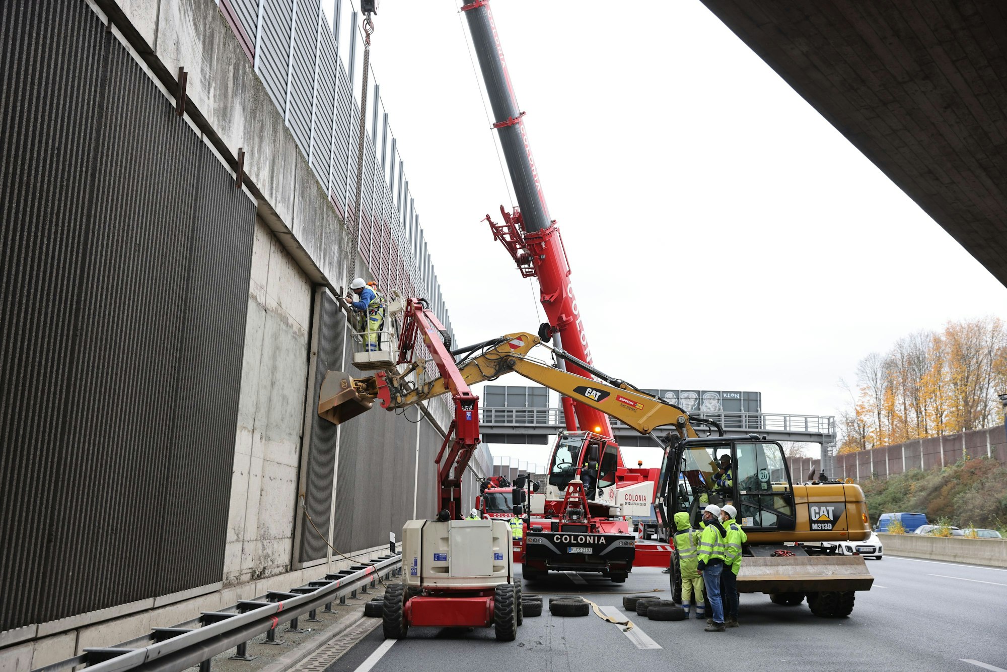 Kriminalbeamte und Mitarbeiter von Straßen NRW untersuchen die Betonplatten an der Lärmschutzwand der A3.