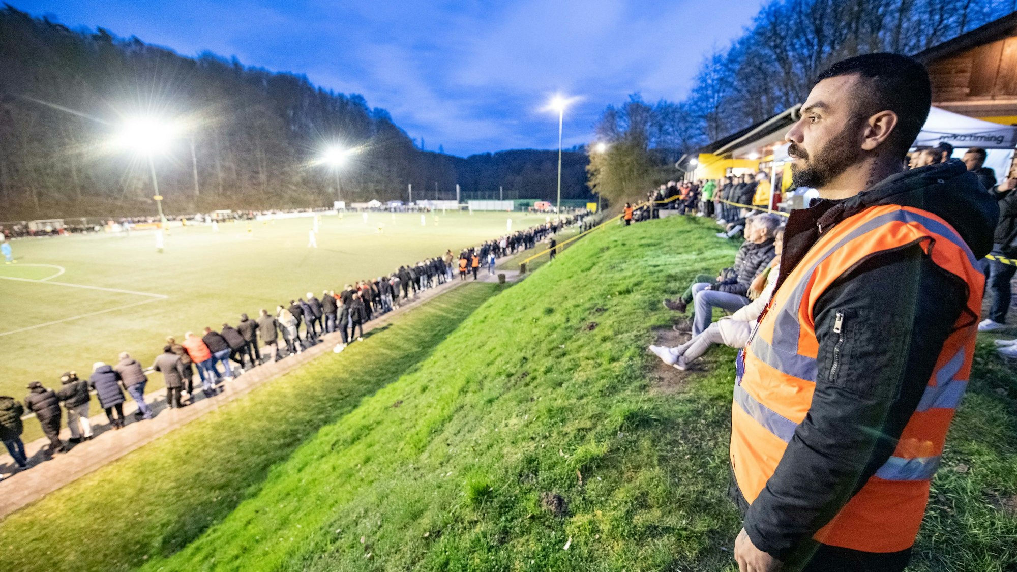 Ein Ordner blickt auf ein beleuchtetes Fußballfeld.