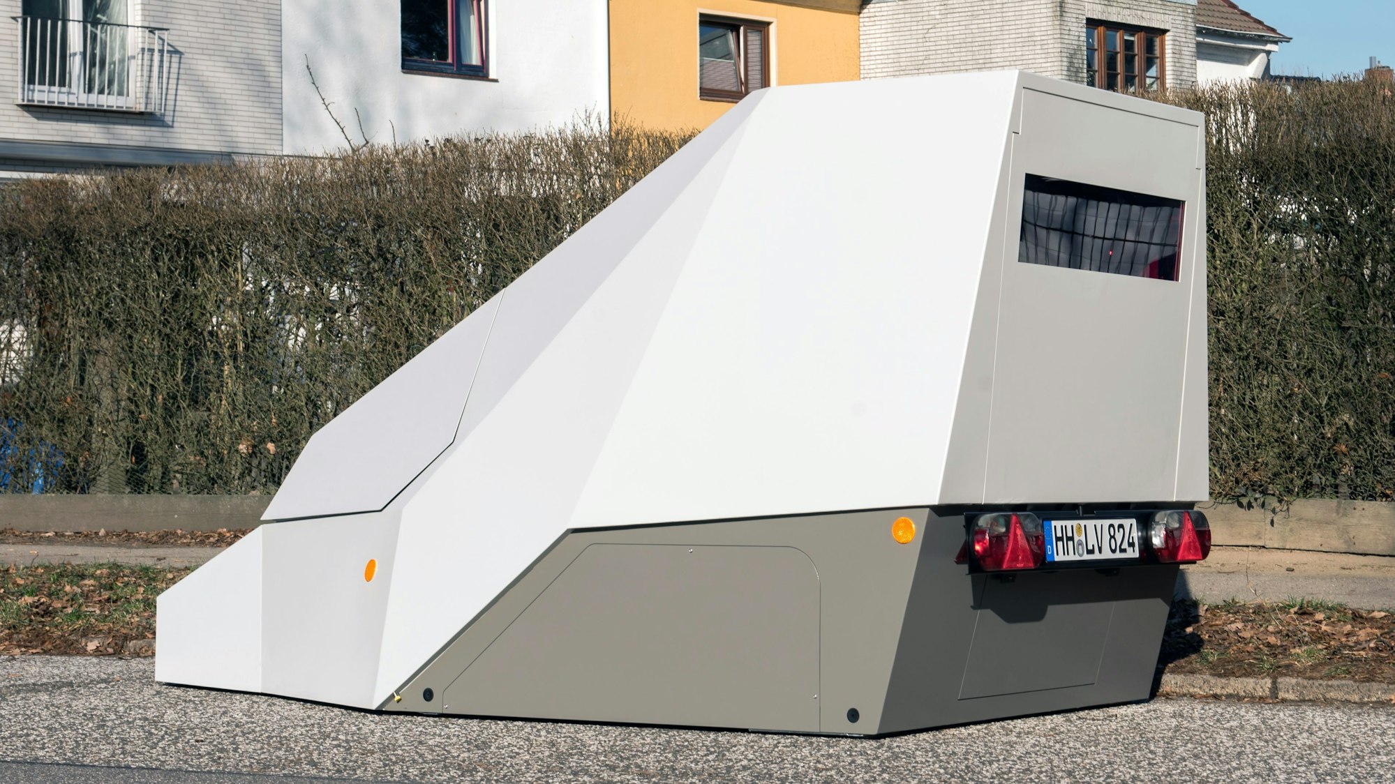 Ein Anhänger zur mobilen Geschwindigkeitsüberwachung steht am Straßenrand.