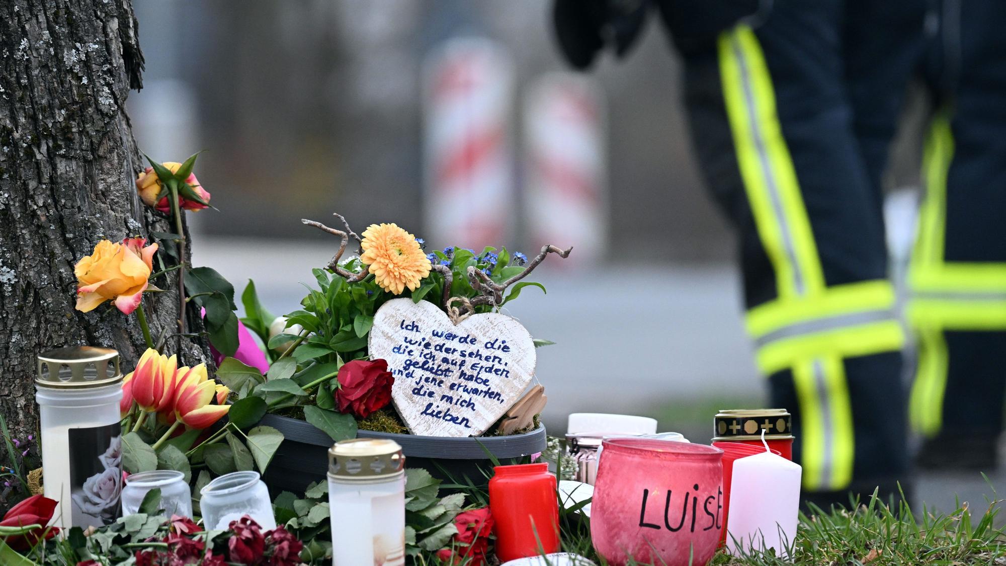 dpatopbilder - 22.03.2023, Nordrhein-Westfalen, Freudenberg: Kerzen und Blumen liegen an einem Baum an der Gesamtschule. Mit einer Trauerfeier nehmen Angehörige der getöteten zwölfjährigen Luise aus Freudenberg im Siegerland Abschied von dem Mädchen. Zwei 12 und 13 Jahre alte Mädchen hatten gestanden, Luise mit Messerstichen getötet zu haben. Foto: Federico Gambarini/dpa +++ dpa-Bildfunk +++