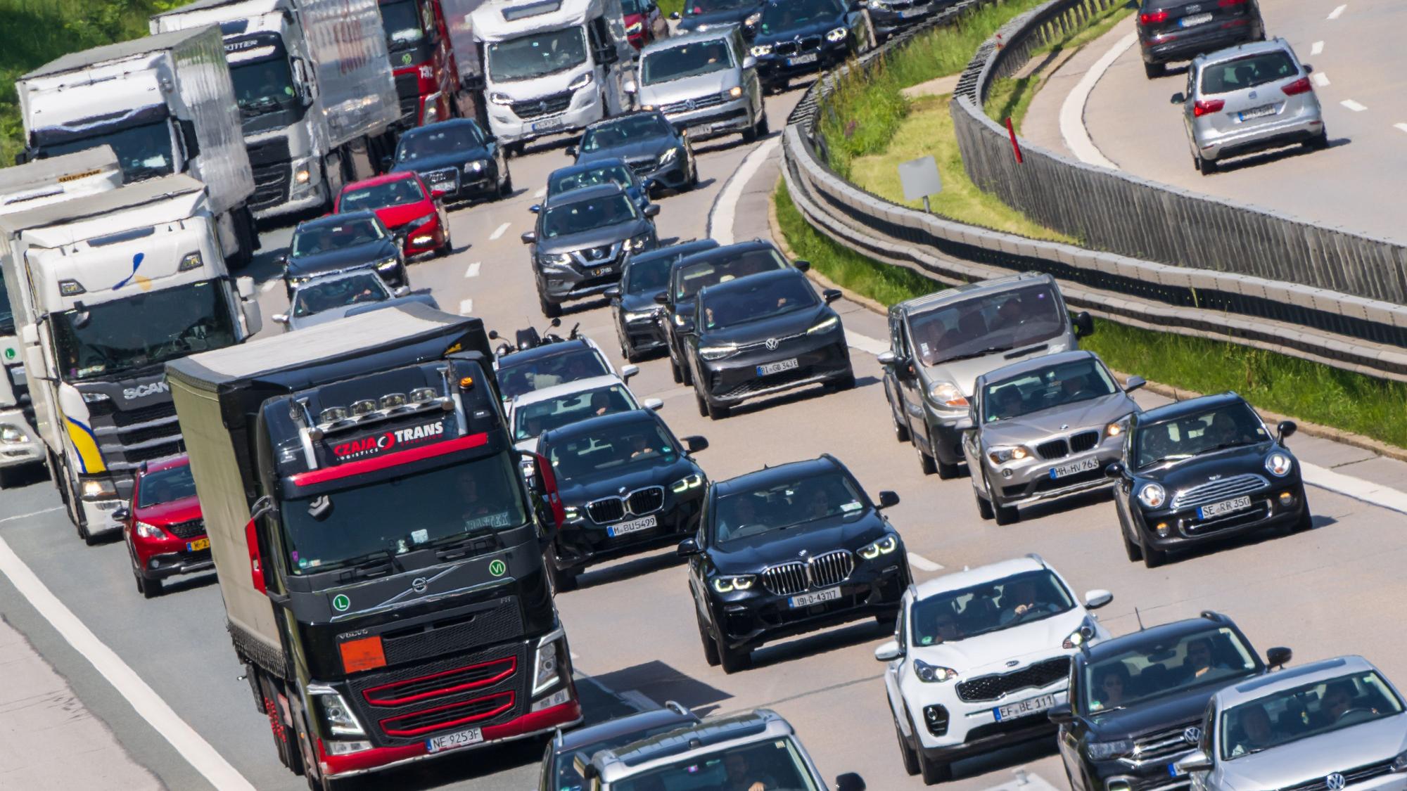 Lkw stehen mit Autos auf einer Autobahn.