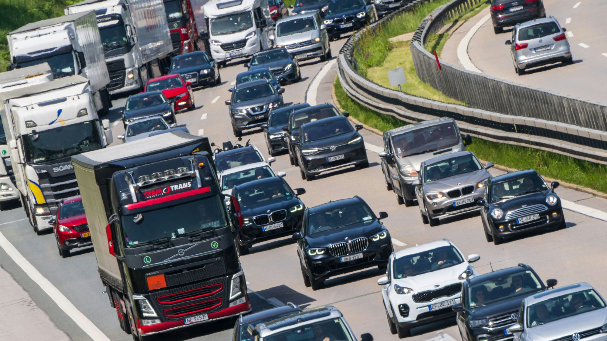 Lkw stehen mit Autos auf einer Autobahn.
