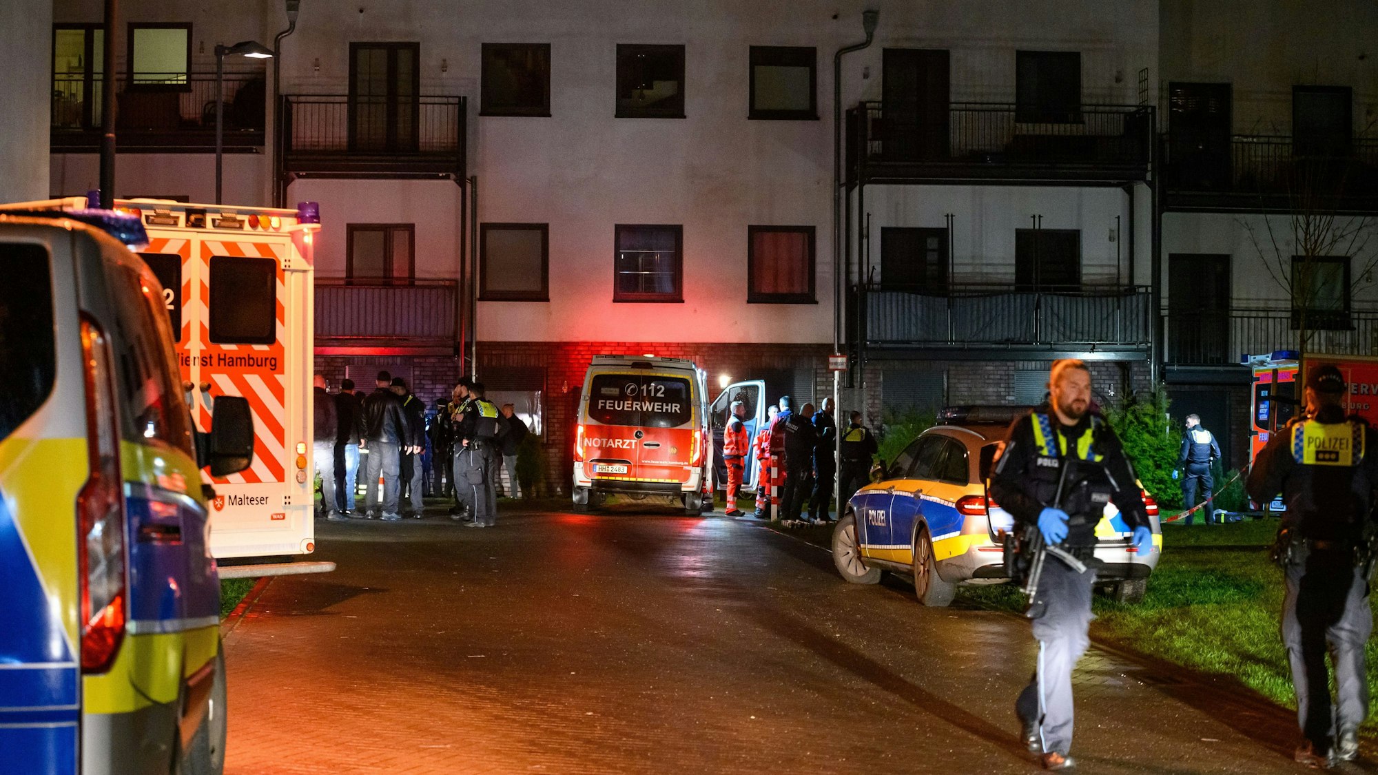 26.03.2023, Hamburg: Polizisten, Ermittler und Rettungskräfte stehen am abgesperrten Tatort.