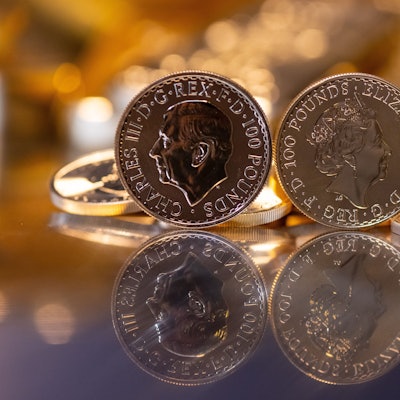 16.03.2023, Bayern, München: Goldbarren und Goldmünzen in unterschiedlicher Größe liegen beim Edelmetallhändler Pro Aurum in einem Tresor auf einem Tisch. Im Vordergrund ist die Goldmünze "Britannia" zu sehen (links mit dem Motiv König Charles III., rechts mit dem Motiv Königin Elizabeth II.)