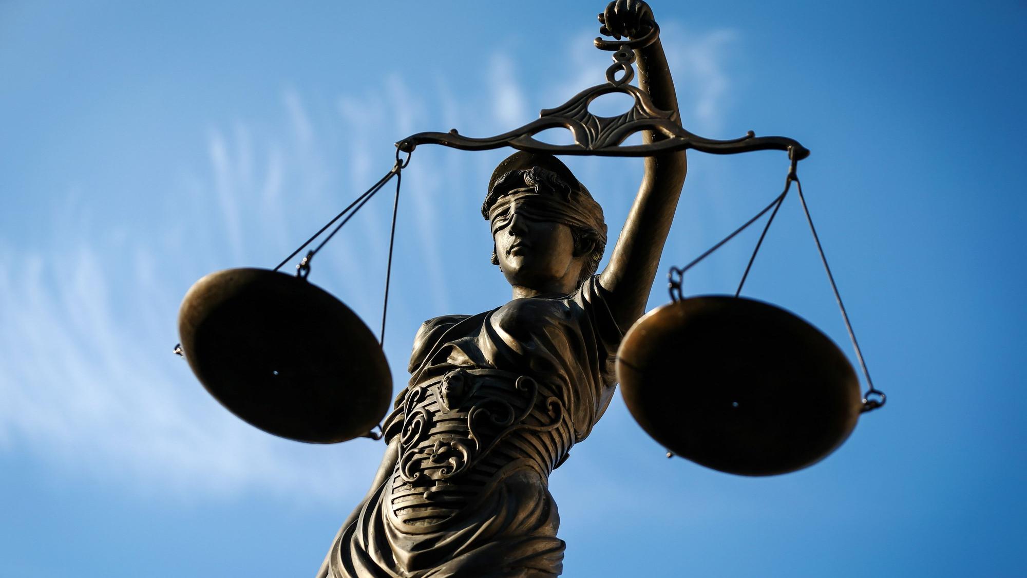 Eine Statue der Justitia hält eine Waage in der Hand.