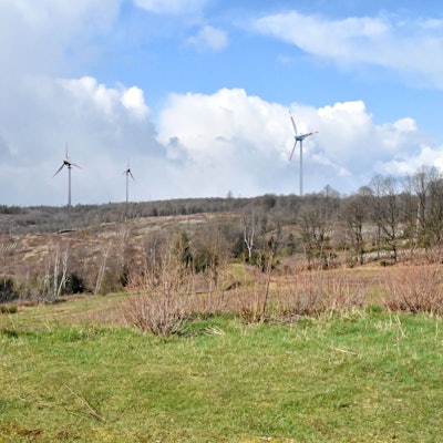 Vier Windräder stehen auf einer kahlen Fläche.