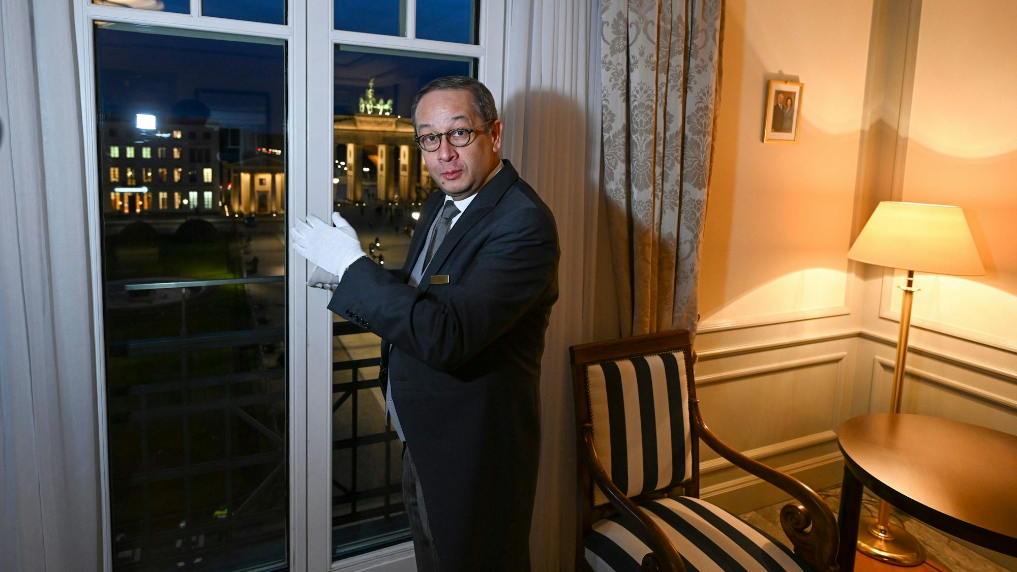 Butler Ricardo Dürner steht in der Royal Suite im Hotel Adlon und präsentiert den Ausblick auf das Brandenburger Tor. Zu manchen Details eines königlichen Besuchs wird traditionell geschwiegen. Insidern zufolge wird König Charles III. wohl dort unterkommen, wo bereits seine Mutter Queen Elizabeth II. zu Gast war. Eine der drei Präsidenten-Suiten wurde im Hotel Adlon ihr zu Ehren zur Royal Suite ernannt. Foto: Jens Kalaene/dpa +++ dpa-Bildfunk +++