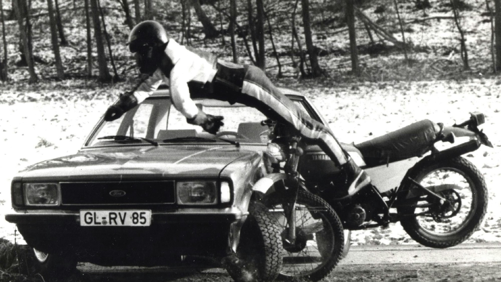 Ein Motorradfahrer fliegt über einen Wagen mit GL-Kennzeichen.