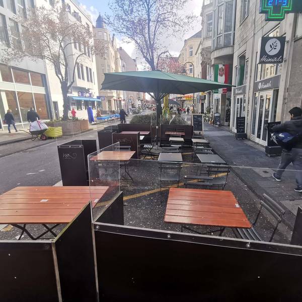 Auf einer Straße stehen Straßenmobiliar einer Gastronomie.