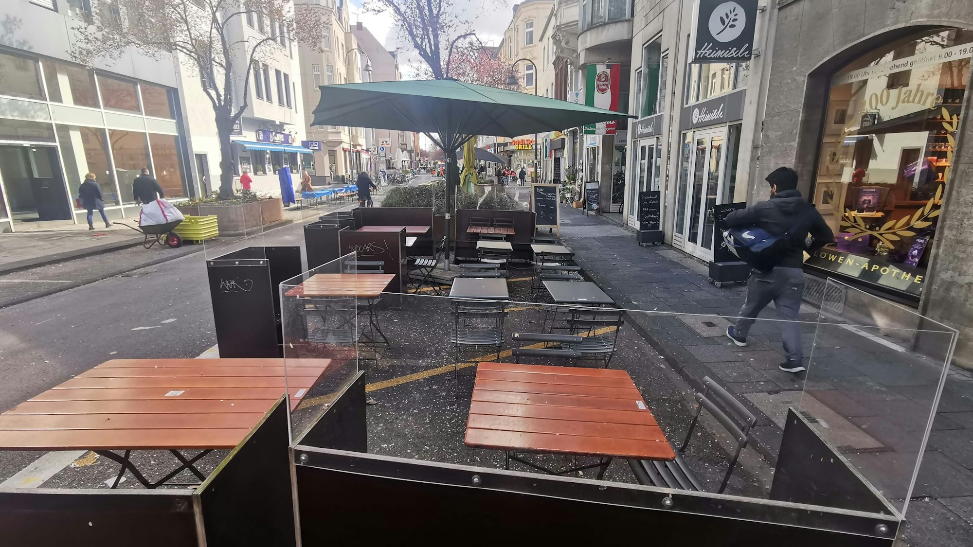 Auf einer Straße stehen Straßenmobiliar einer Gastronomie.