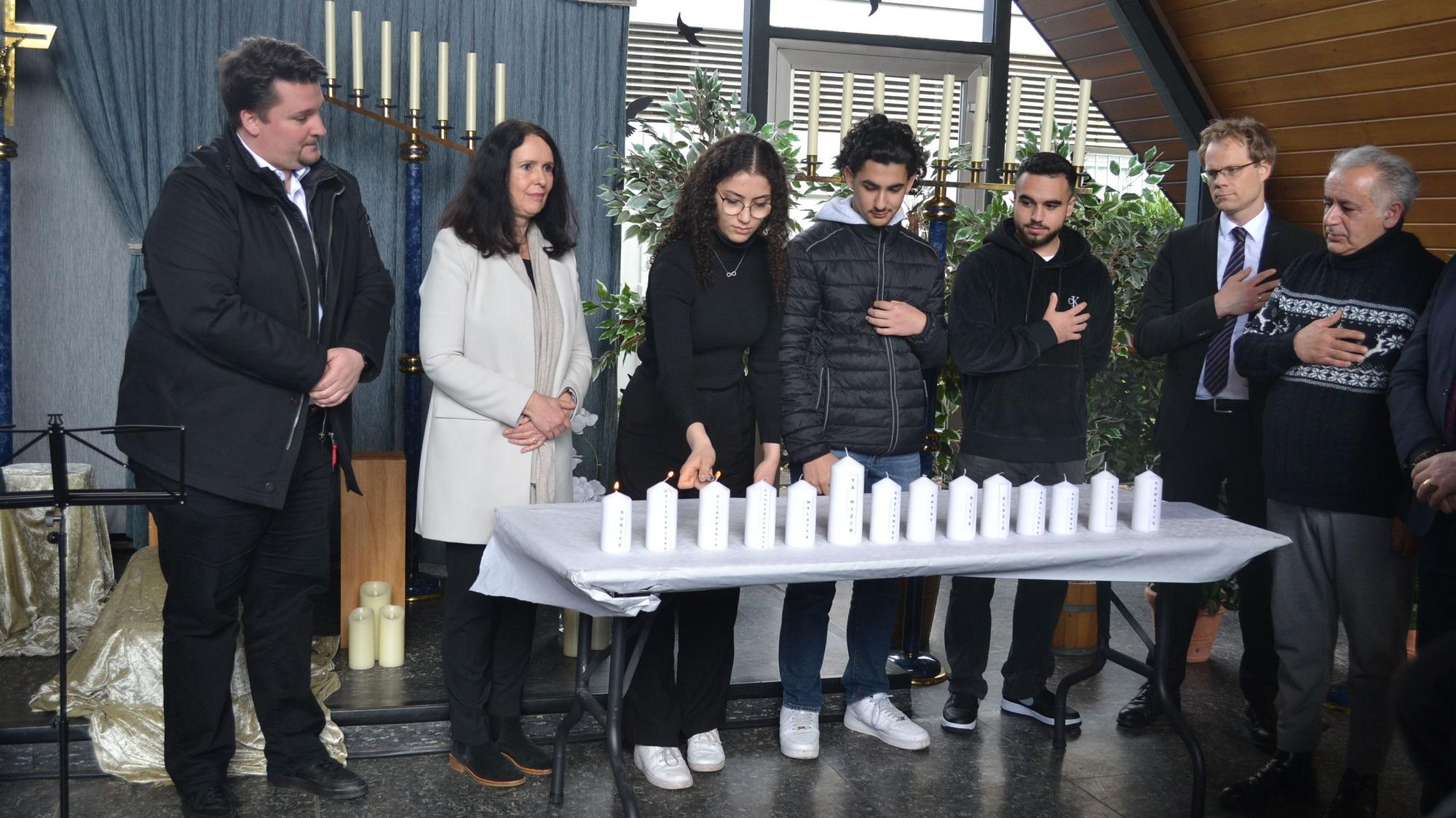 Mehrere Menschen stehen vor einem Tisch mit Kerzen.