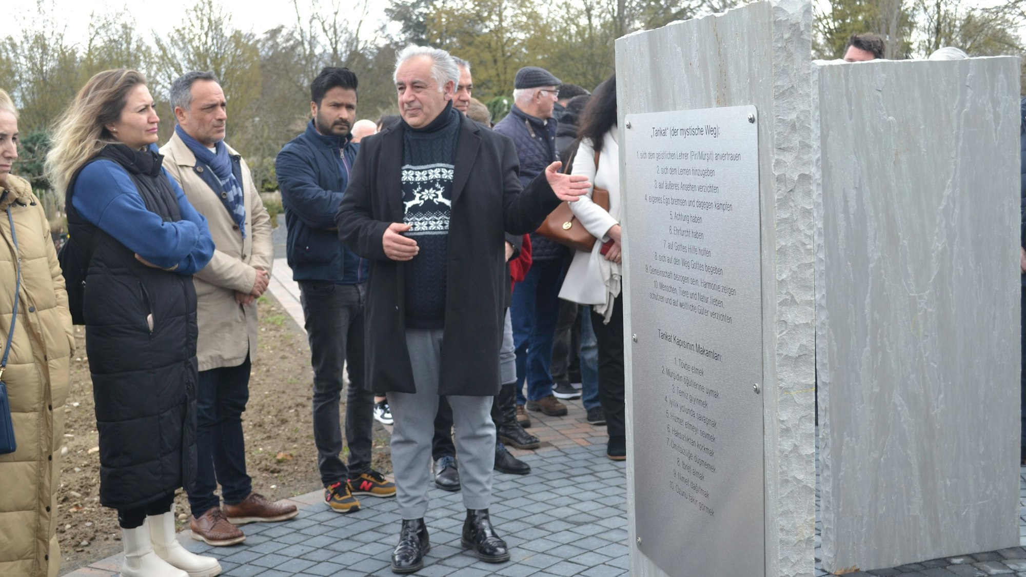 Mehrere Personen stehen an einer Stele.