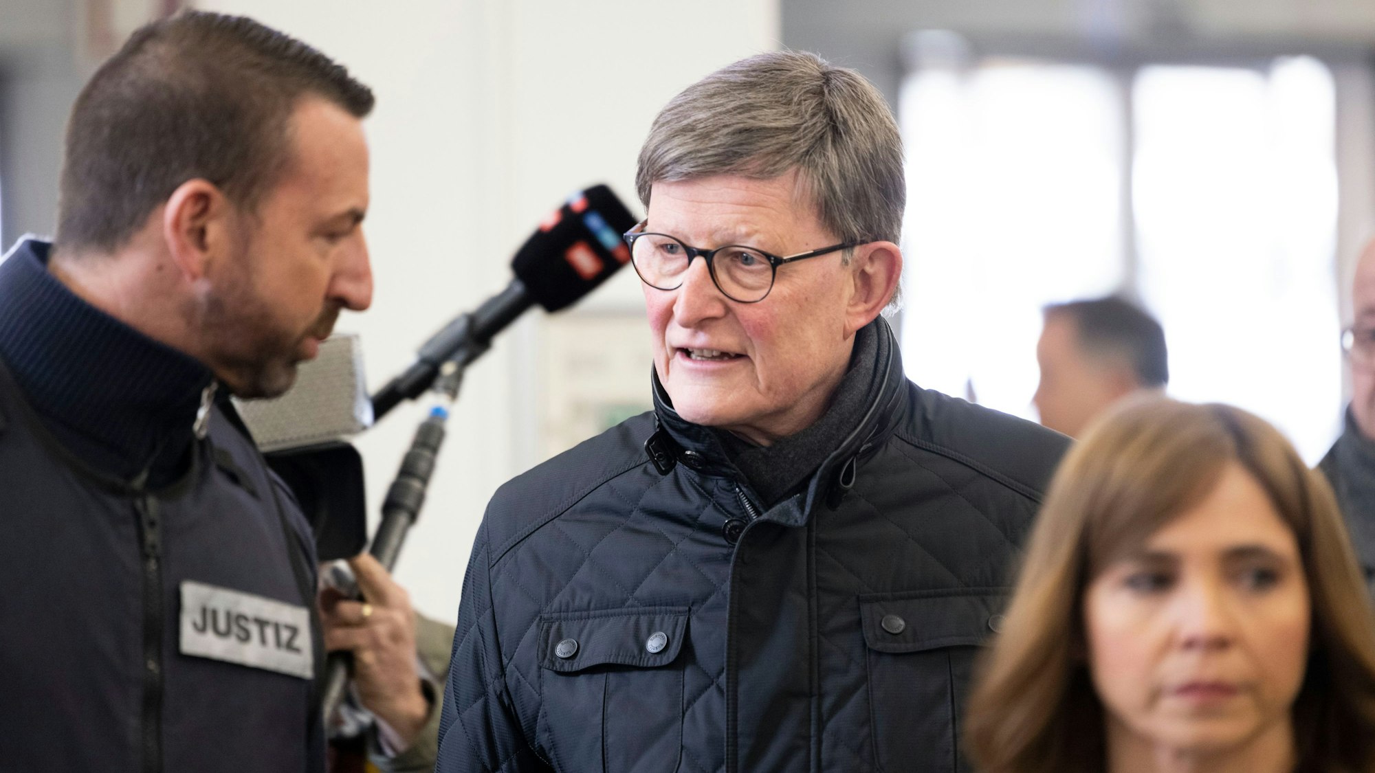 28.03.2023
Köln, NRW
Kardinal Rainer Maria Woelki (2.v.l) wird im Foyer des Landgerichts von einem Justizbeamten zur Sicherheitsschleuse begleitet.