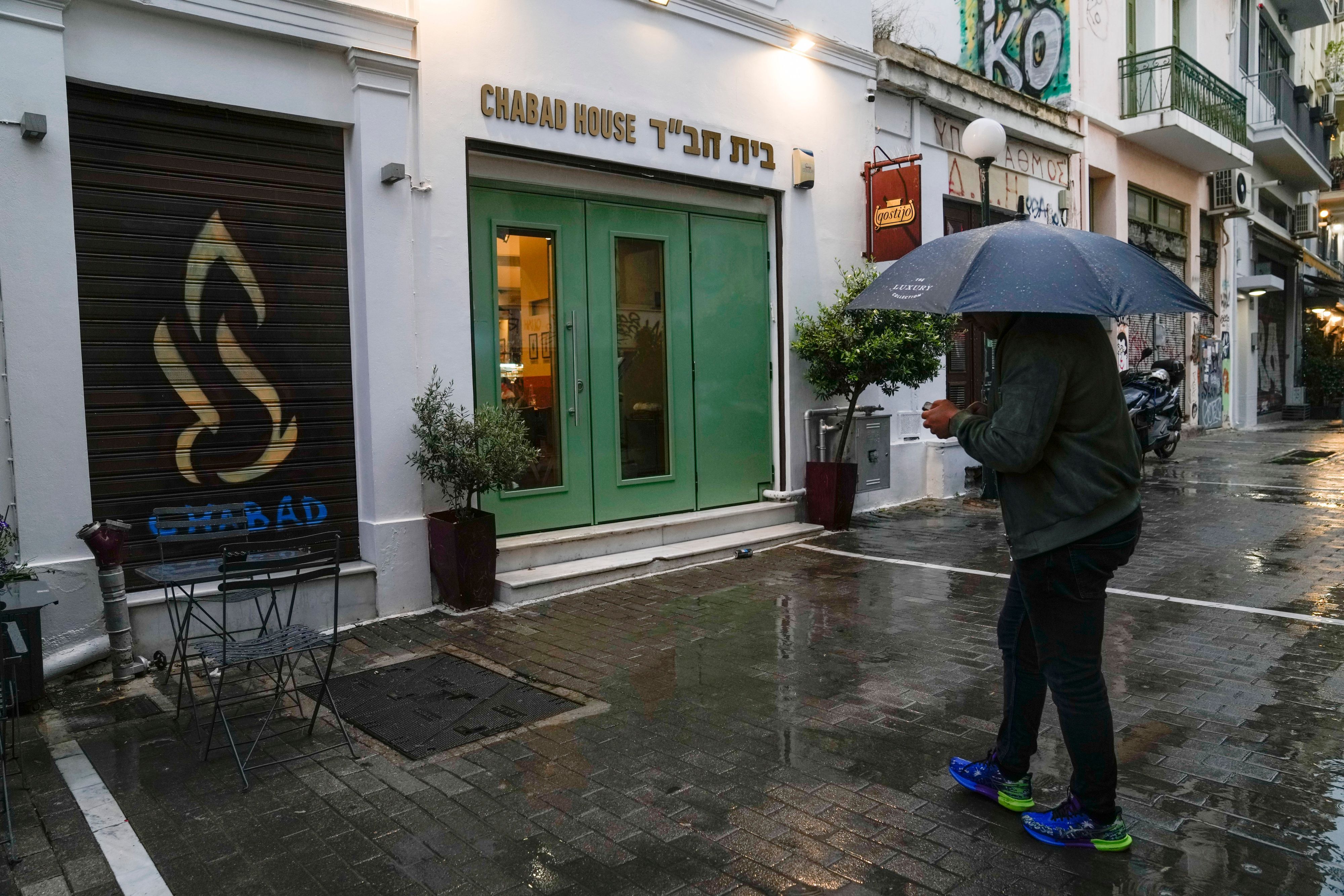 Ein Mann mit Regenschirm steht vor einem jüdischen Restaurant in Athen.