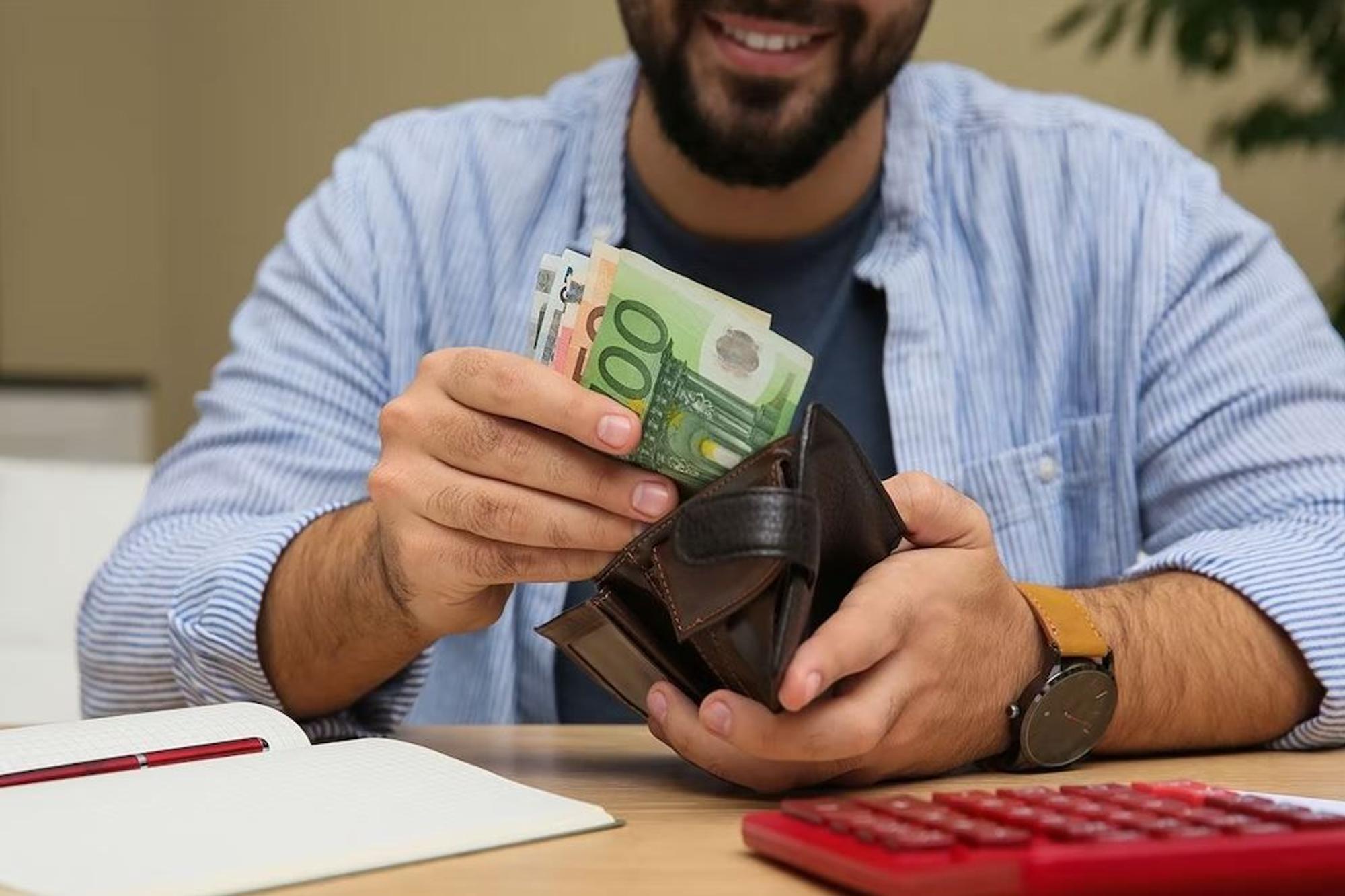 Mann zieht Euro Geldscheine aus der Geldbörse.