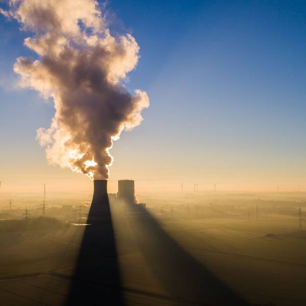 Die Sonne geht hinter dem Kraftwerk Mehrum im Landkreis Peine auf. Im Hintergrund stehen mehrere Windkrafträder.