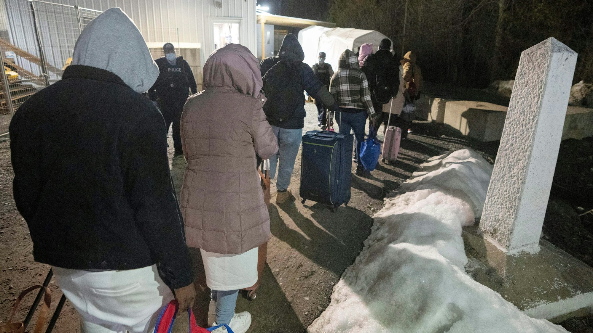 Menschen mit Koffern stehen in einer Reihe.