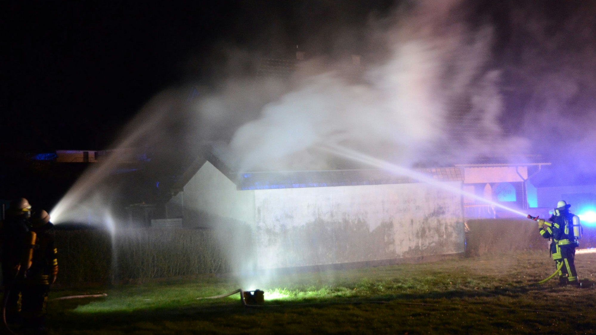Das Foto zeigt Feuerwehrleute, die den Brand mit ihren Strahlrohren bekämpfen.